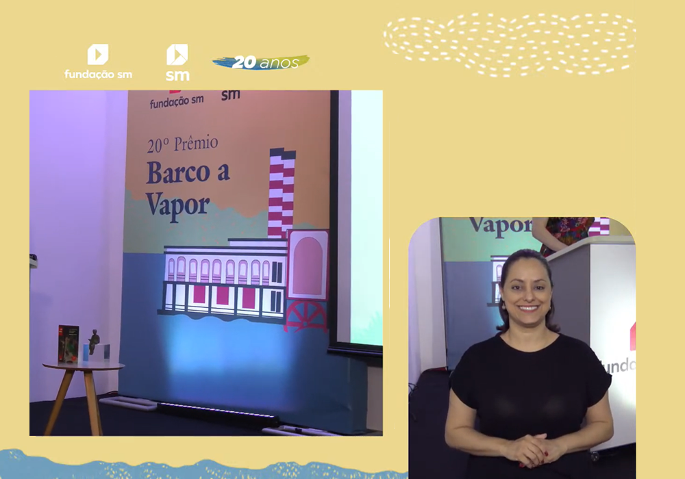 Captura de tela de uma transmissão ao vivo no YouTube.

O fundo da imagem é amarelo pastel. No canto superior esquerdo, há pequenos pontos brancos que formam o desenho de uma nuvem.

No canto inferior direito, há um desenho de mar com uma textura que lembra giz de cera. 

Do lado esquerdo, está um banner em que se lê: 'Fundação SM. 20º Prêmio Barco a Vapor'.

No lado direito, Vânia aparece sorrindo. Seu cabelo está na altura do pescoço e está preso para trás.

Ela usa uma camiseta preta com mangas curtas. 

Tem mãos juntas na frente do tórax e as unhas pintadas de vermelho.