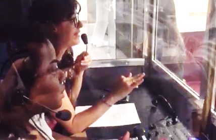 Vânia Santiago falando no microfone dentro de uma cabine de interpretação.