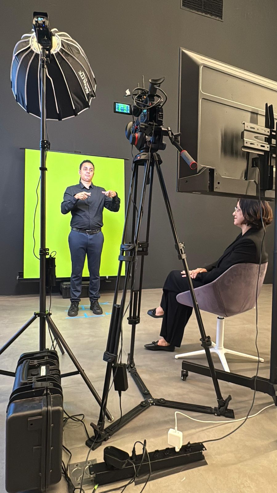 Vânia Santiago assiste o colega interpretar. Esse colega está de frente a uma tela verde.