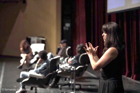 Vânia Santiago está em cima de um palco sinalizando em Libras.