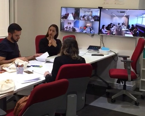 Vânia Santiago sinaliza em Libras em uma mesa de reunião.